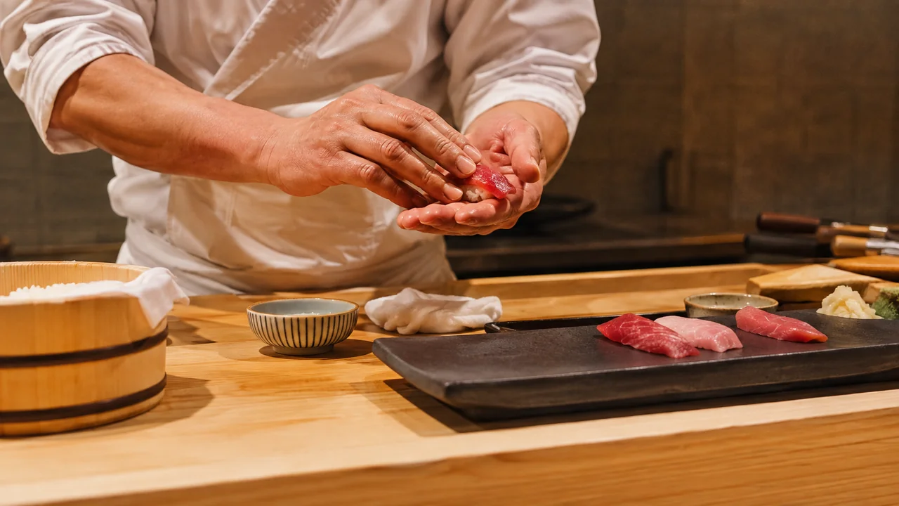 Geleneksel Tokyo suşi tezgâhında sirkeli pirinç ve ton balığıyla nigiri biçimlendiren ustanın elleri
